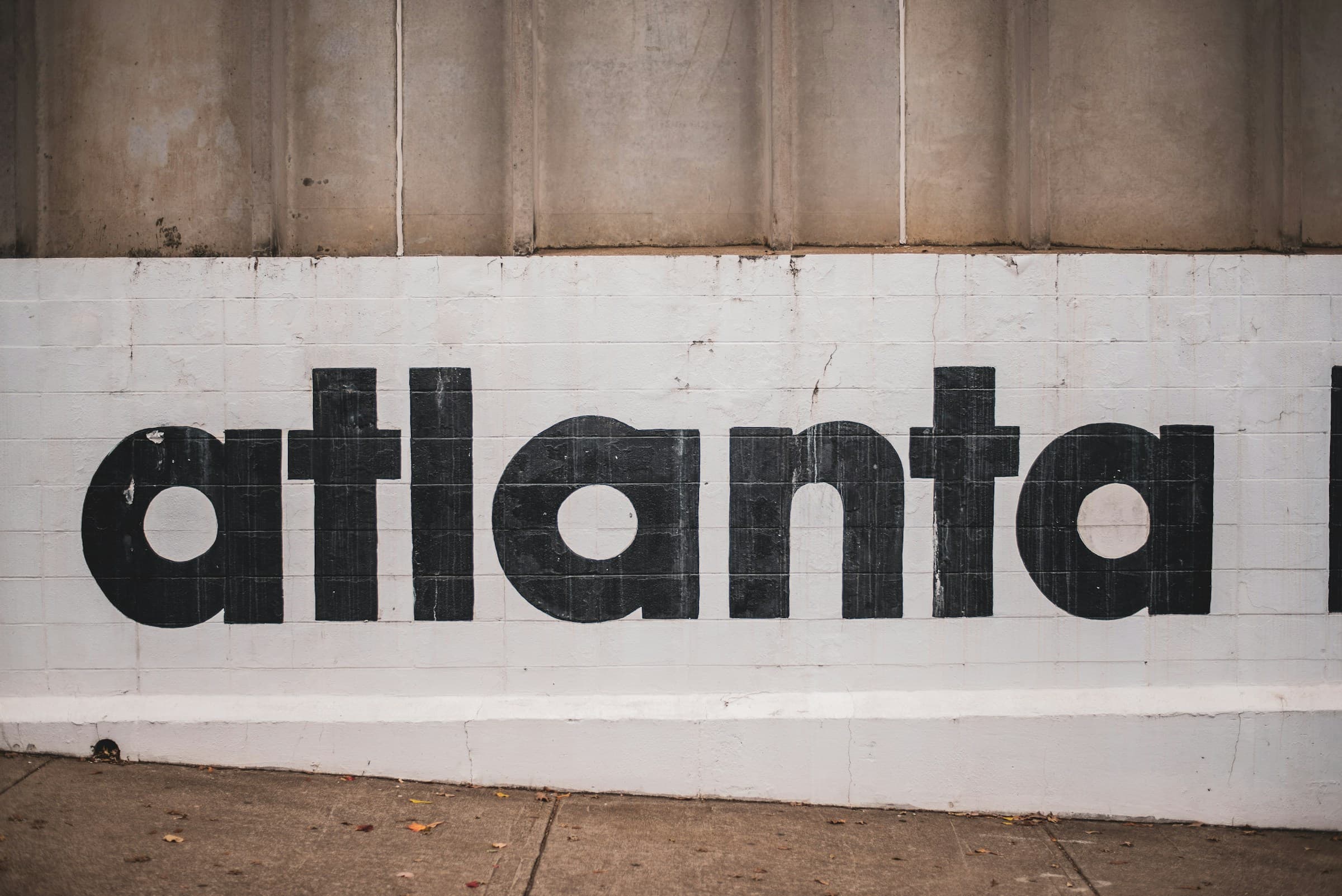The word 'atlanta' painted in black lowercase letters across a white brick wall.